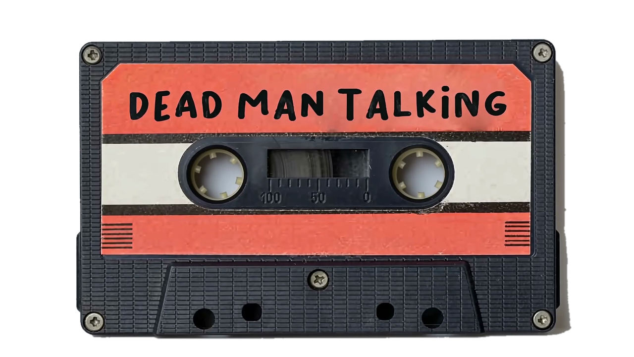 A black cassette tape with a coral label, the words Dead Man Talking hand-lettered across it.
